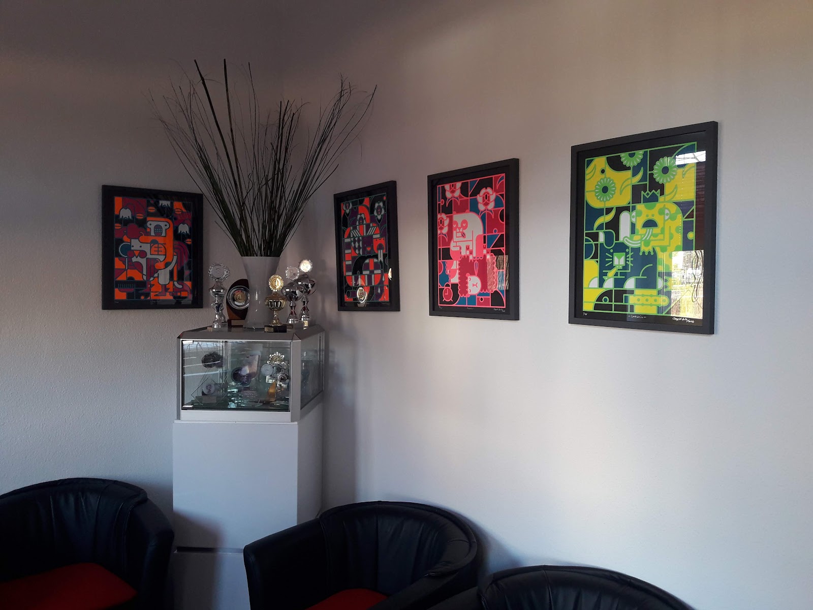 Wartebereich mit Kunstdrucken und Pokalvitrine